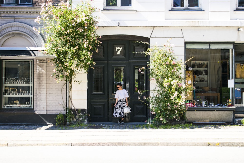 woman carrying bag white standing in front of door during daytime