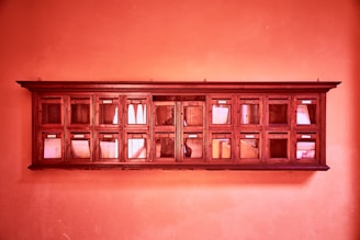 A wooden wall-mounted organizer with multiple small compartments containing papers. The warm, reddish-orange lighting gives the scene a nostalgic or vintage feel.