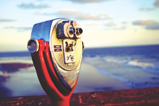 person holding red and silver coin operated telescope in Santa Ana United States