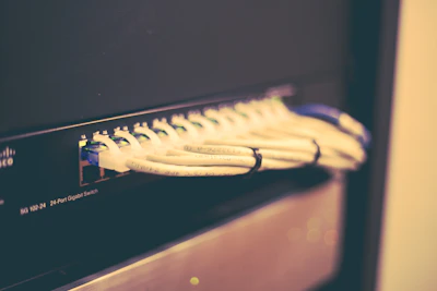 Stack of used networking switches and routers neatly arranged on a wooden table