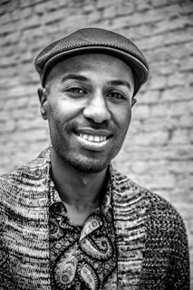 A customer holding a custom t-shirt with a coal mining village image, smiling in front of a brick wall.