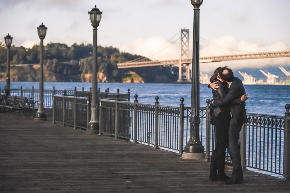 man and woman kissing beside metal rail guard