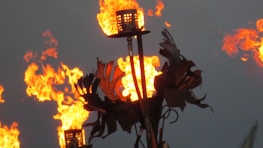 Torches with open flames flicker brightly against a dusky background, surrounded by metal decorative elements.
