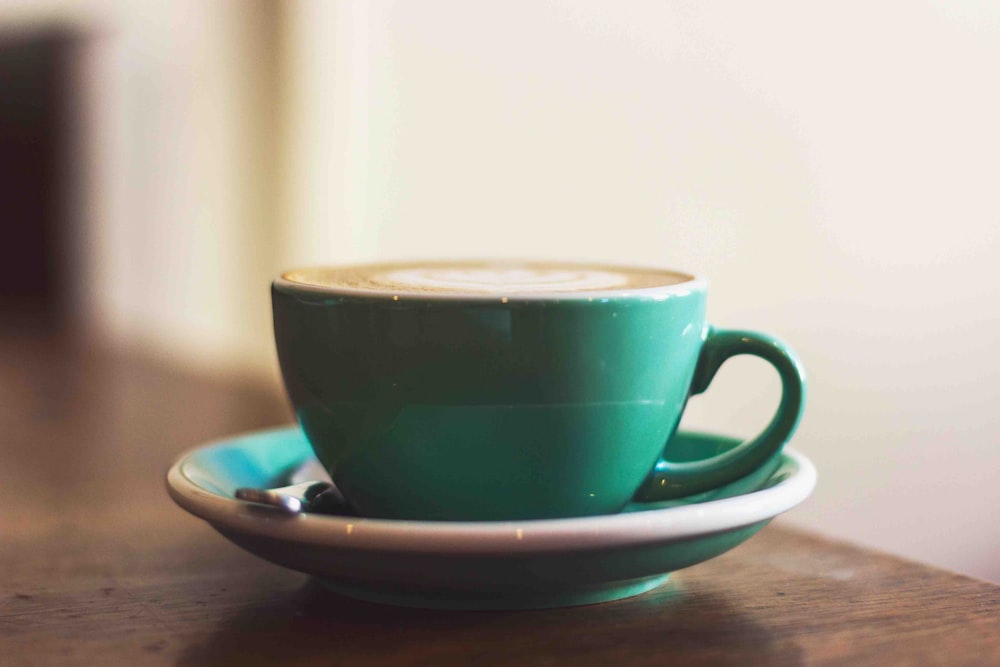 Selektive Fokusfotografie einer Tasse Kaffee auf grüner Untertasse