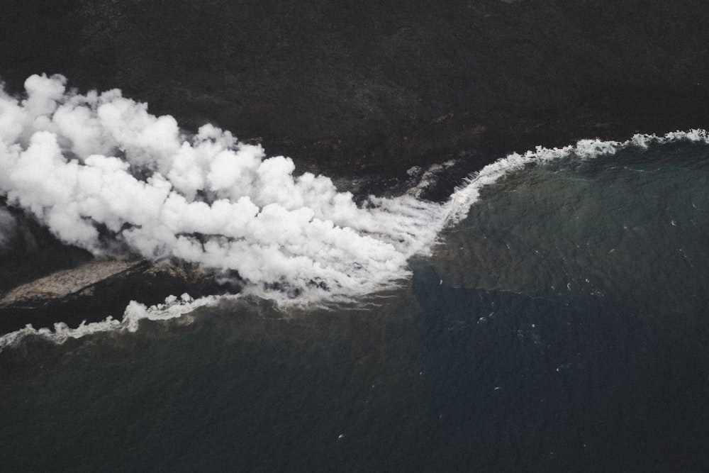 an aerial view of smoke coming out of the ocean