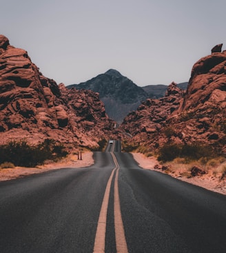 black concrete road surrounded by brown rocks