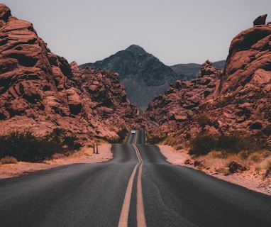 black concrete road surrounded by brown rocks