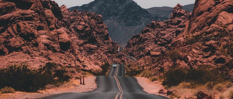 black concrete road surrounded by brown rocks