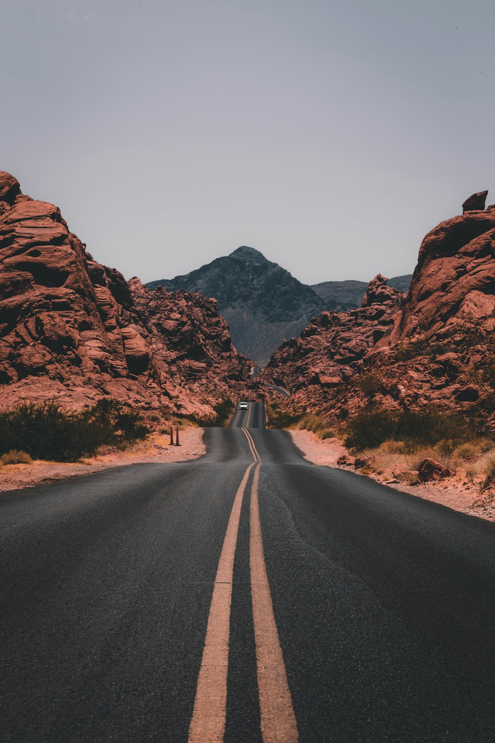 black concrete road surrounded by brown rocks