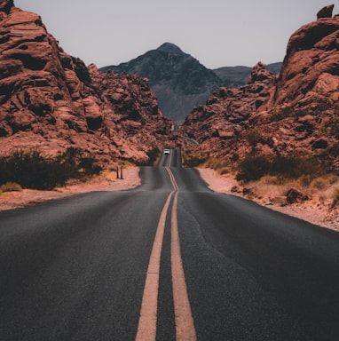 black concrete road surrounded by brown rocks