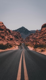 black concrete road surrounded by brown rocks