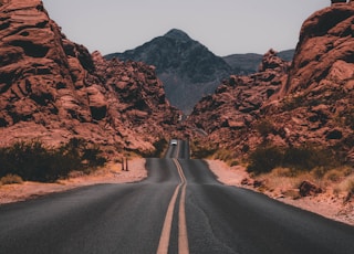 black concrete road surrounded by brown rocks