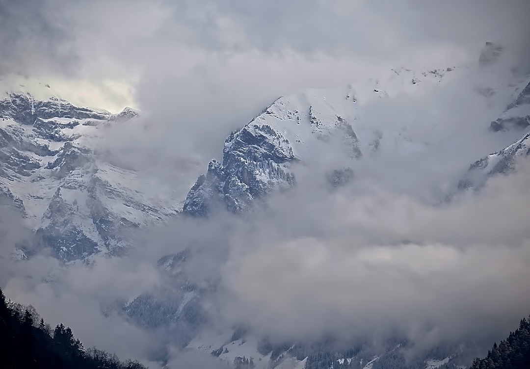 mountain covered by snow under white clouds