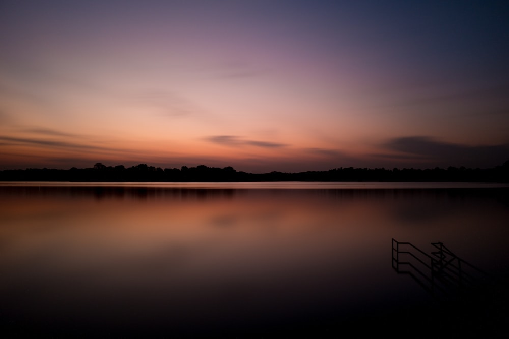 body of water under orange cloudy sky