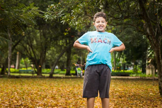 A young boy in a bright blue t-shirt and comfortable shorts playing in a park