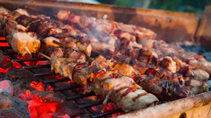 Close-up of glowing embers beneath sizzling skewers of meat at the ocak başı.