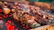 A softly lit close-up of a glowing charcoal grill with flames flickering beneath sizzling skewers.