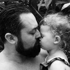 A father and child sharing a quiet moment outdoors, surrounded by native New Zealand flora.