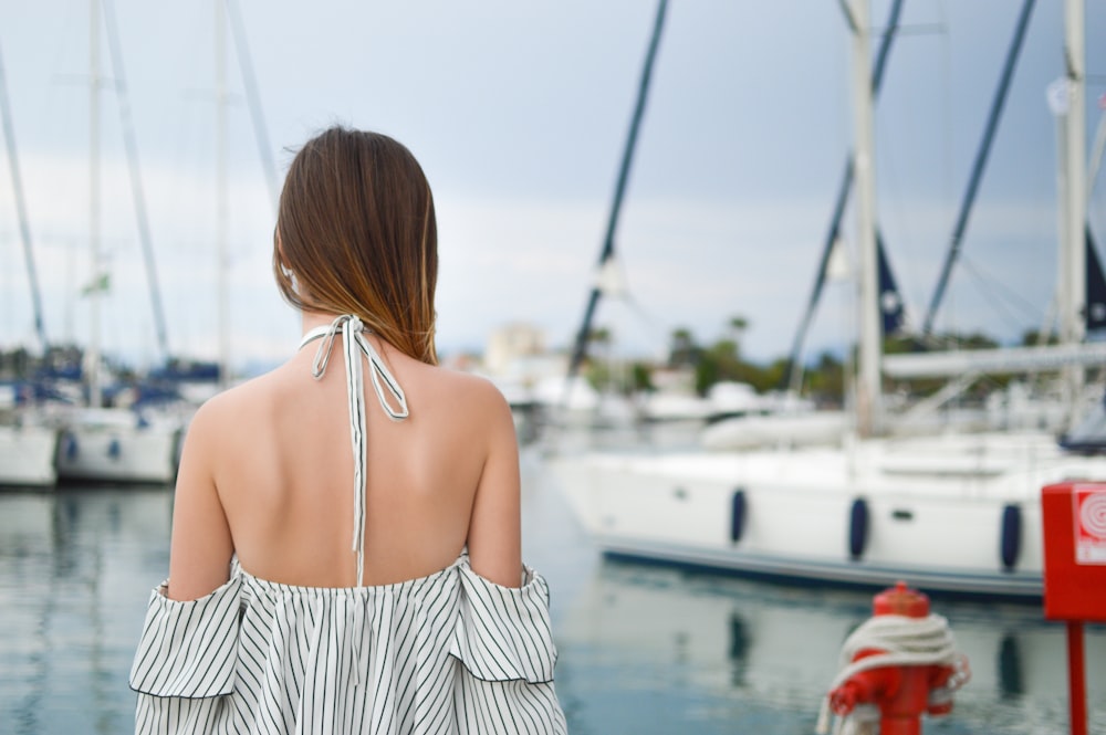 woman in black and white striped cold-shoulder halter top near white yacht