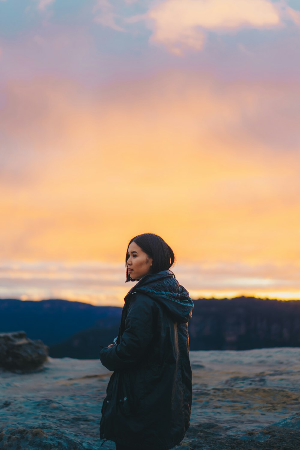 woman in black jacket standing on hill during daytime