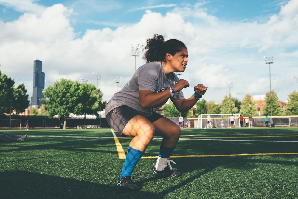 woman doing squat on green field during daytime