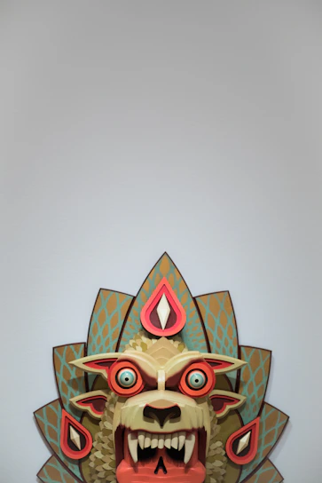 Stylized lucha libre mask in teal, coral, yellow, and gold colors.