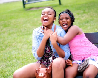 Two young people sitting on a park bench, talking and sharing a laugh during a peer mentoring session.