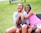 Two girls playing together in matching outfits, laughing outdoors.