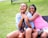 Two girls playing together in matching outfits, laughing outdoors.