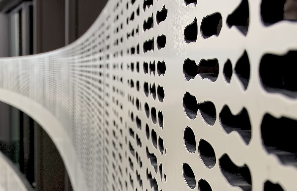 a close up of a white bench with holes in it