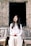 woman in white button-up dress shirt and white pants holding apple sitting on chair