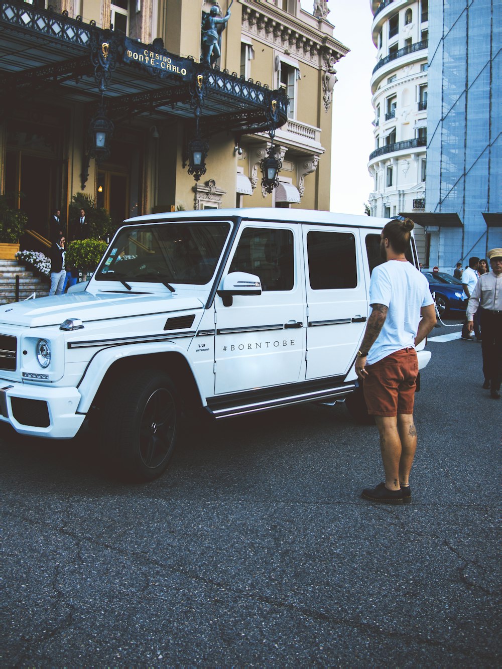 man standing beside white SUV during daytime