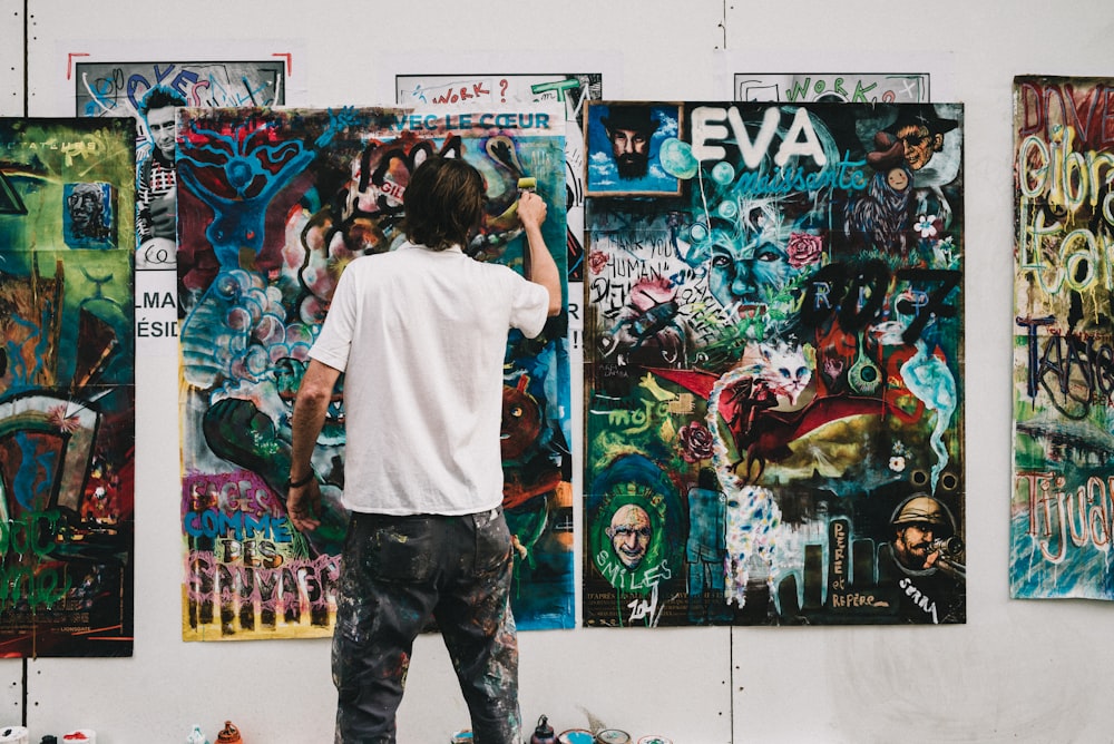 man wearing white shirt painting a wall