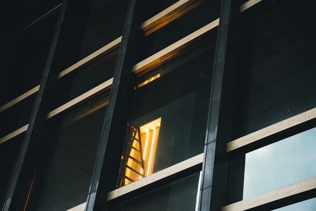 Abstract shot of layered glass panels reflecting warm gold light on a white surface.