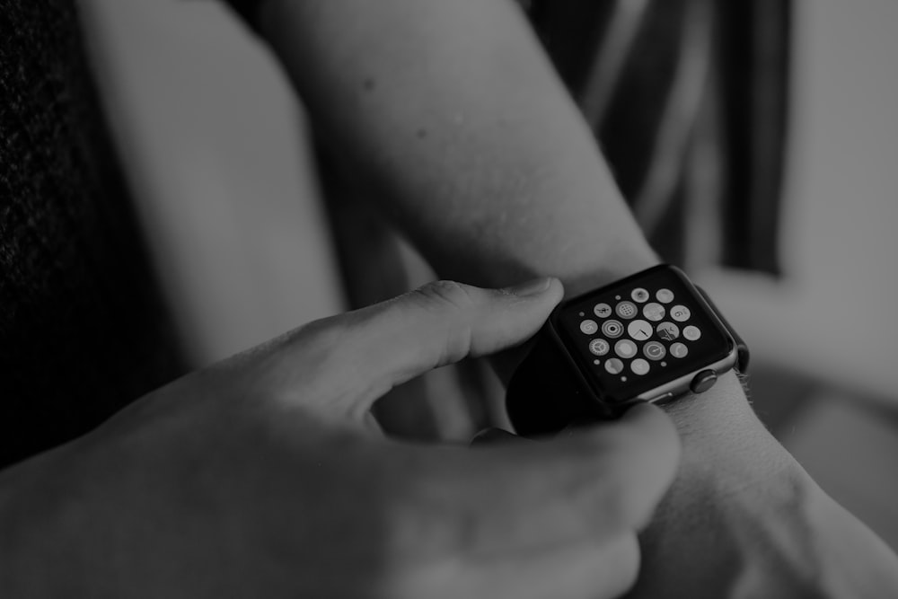 grayscale photo of person using Apple Watch