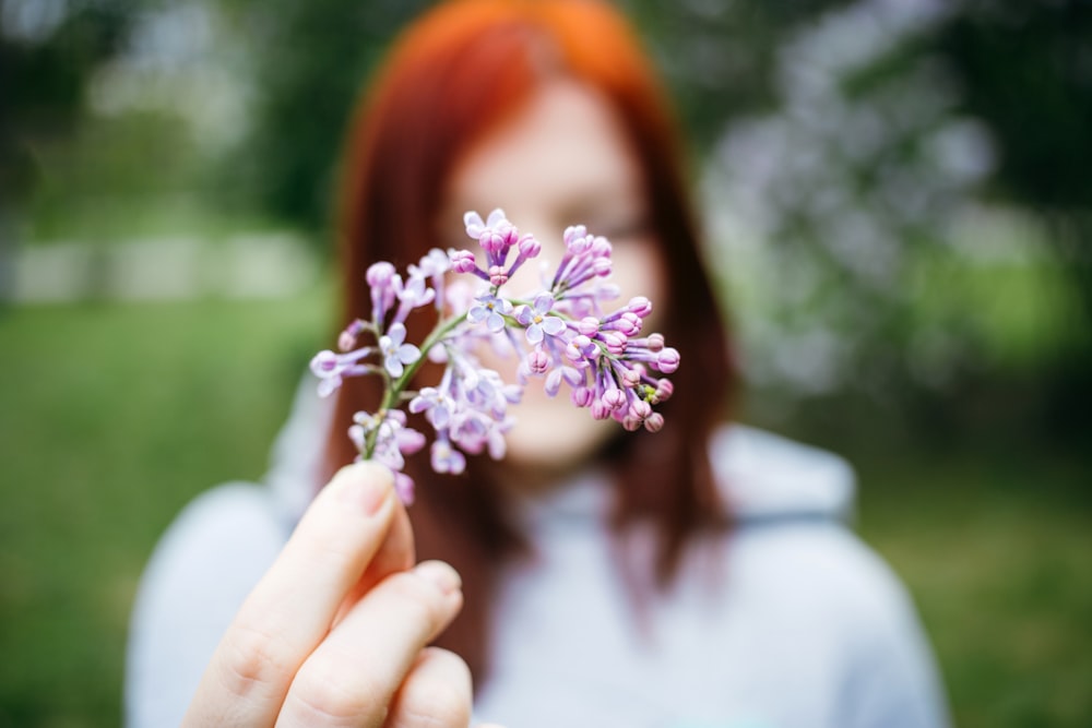 macro shot photo of woman holding purple flower standing outside