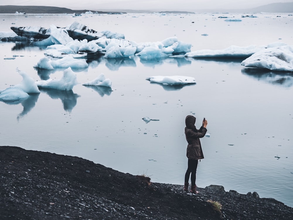 woman taking photo standing near body of water