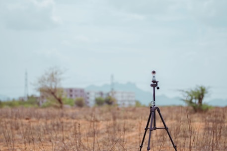 A lightweight tripod set up on uneven ground overlooking a misty field at dawn, ready for predator hunting.