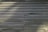 Corrugated metal sheets are aligned vertically with visible screws and a central seam. The surface appears weathered with some discoloration and shadows cast across it.