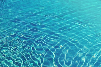 Close-up of crystal-clear pool water reflecting sunlight with gentle ripples.
