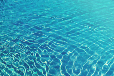 Clear swimming pool with sparkling blue water under bright sunlight.