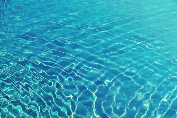 Close-up of crystal-clear pool water reflecting sunlight with gentle ripples.