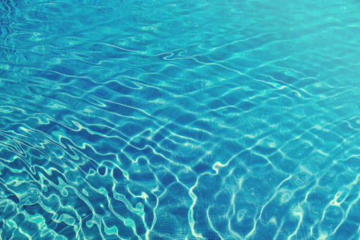 A sparkling blue pool with gentle ripples reflecting sunlight on a clear summer day.