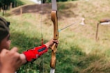 person using bow aiming person from afar during daytime