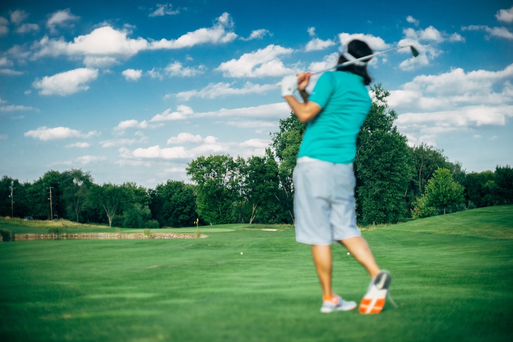 hombre con el palo de golf oscilado en el campo durante el día