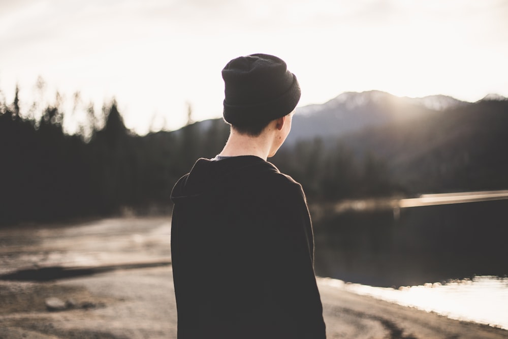 tilt shift lens photography of man standing near body of water