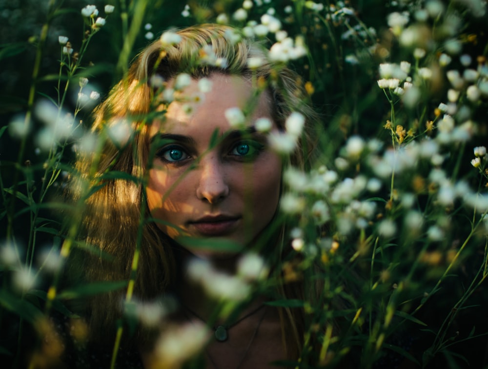mujer detrás de flores de pétalos blancos