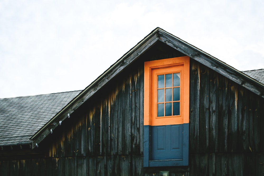 orangefarbene und schwarze Holztür auf dem Dach des Hauses