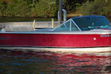 A classic used motorboat docked at a sunny marina with reflections on the water
