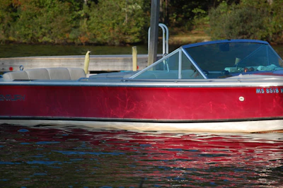A classic used motorboat docked at a sunny marina with reflections on the water